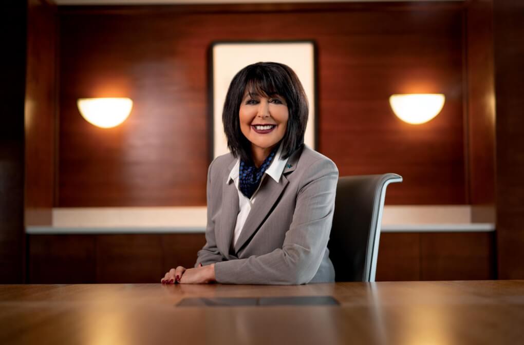 President Philomena Mantella smiles from a desk in a wood paneled room.
